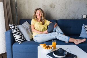 Woman sat comfortably in blue sofa Image by marymarkevich via freepik