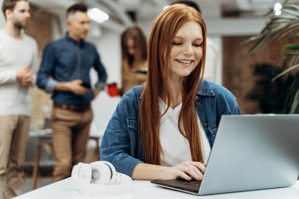 Woman at work with colleagues in background Image by freepik