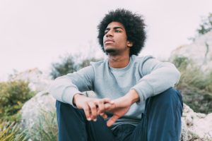 black man sat in grass at peace Image by freepik