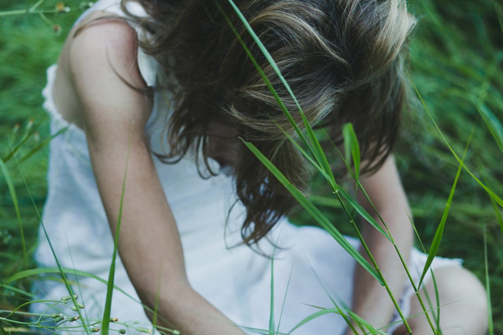 Faceless woman sat in field Image by freepik