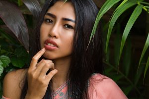 close up portrait of beautiful thai woman over tropical leaves Image by svetlanasokolova on freepik